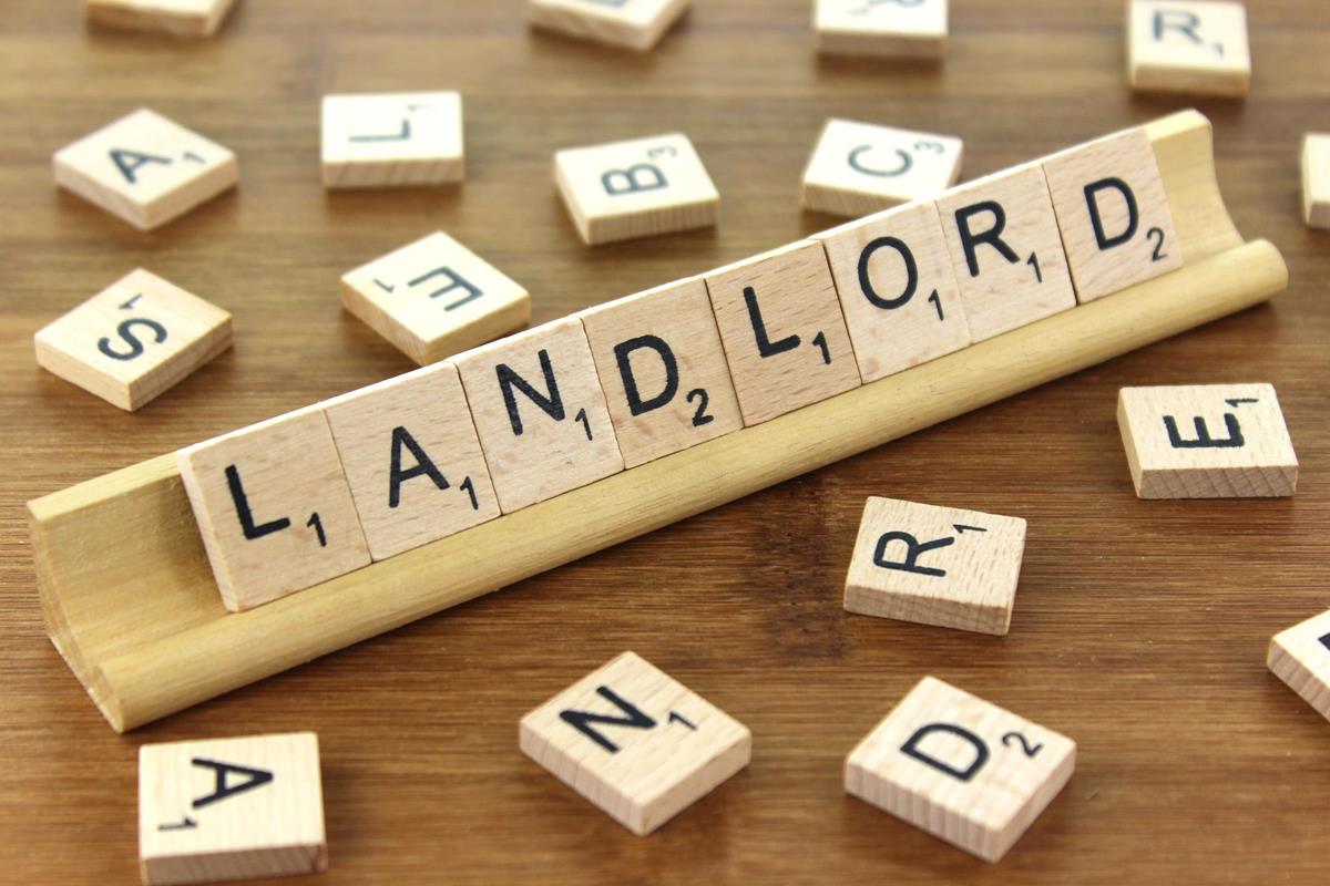 Landlord is spelled out with scrabble tiles surrounded by miscellaneous letters strewn across the table