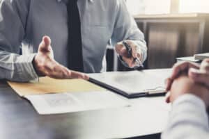 Photo of hands gesturing at A deposition taking sworn testimony. Sworn testimony is evidence taken from a witness that affirms to tell the truth.