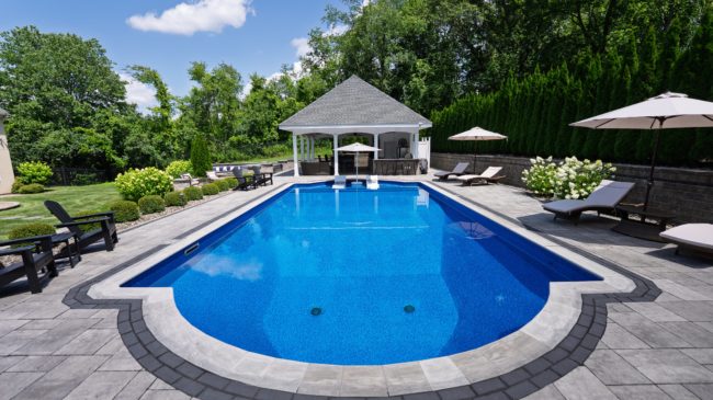 photo of a pool in a backyard with a gazeebo at the end