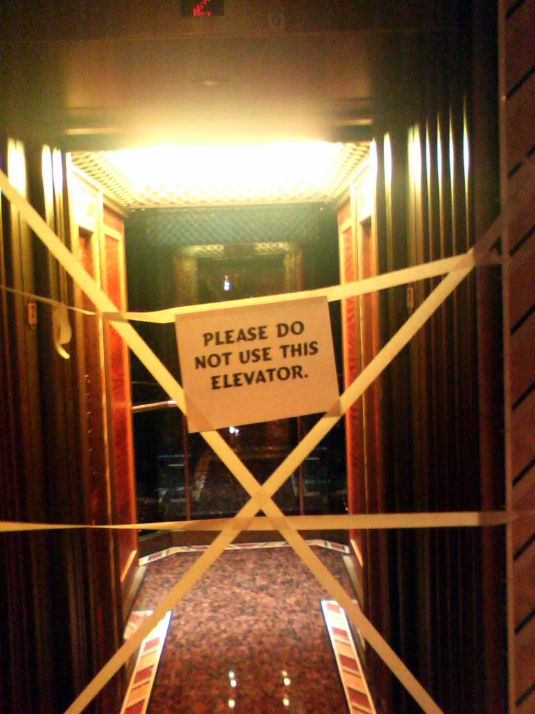 broken elevator with yellow tape and sign stating not to enter